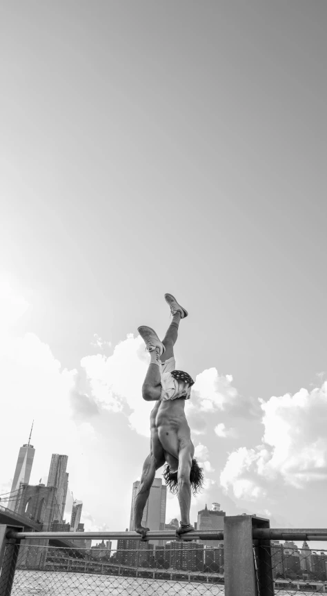 a black and white photo of a person doing a handstand, a statue, inspired by Garry Winogrand, conceptual art, chicago skyline, 8k photo, sunny summer day, circus performance