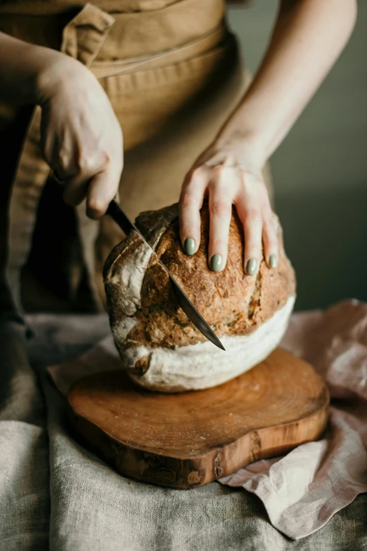 a woman cutting a loaf of bread on a cutting board, a still life, trending on pexels, renaissance, spherical, botanicals, large tall, sculptural