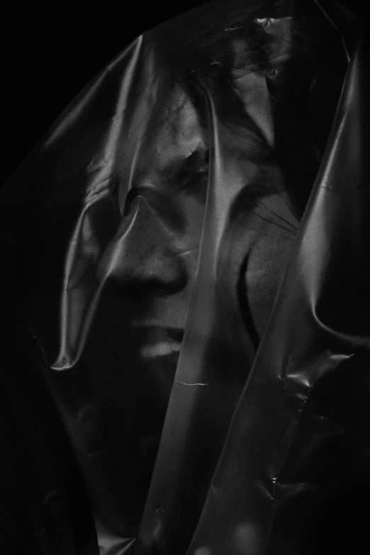 a black and white photo of a man holding a knife, an album cover, by Anna Füssli, hyperrealism, dark hooded wraith, covered in transparent cloth, draped in shiny oil, dren from splice