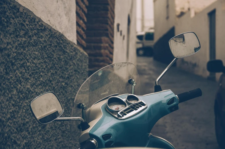 a motor scooter parked on the side of a street, by Matija Jama, trending on unsplash, driving through a 1 9 5 0 s town, white and teal metallic accents, helmet view, 🚿🗝📝