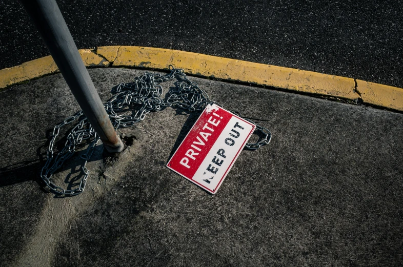 a red and white sign sitting on the side of a road, by Matt Cavotta, unsplash, street art, dragging a pile of chains, outside in parking lot, splash image, sinkhole