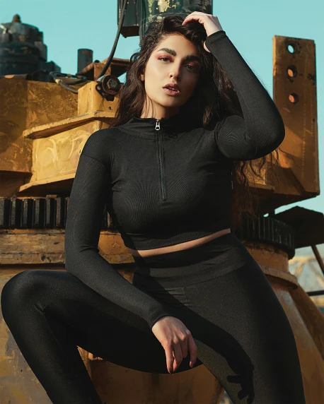 a woman sitting on top of a bulldozer, by Robbie Trevino, tracksuit, wearing black tight clothing, official product image, cinematic outfit photo