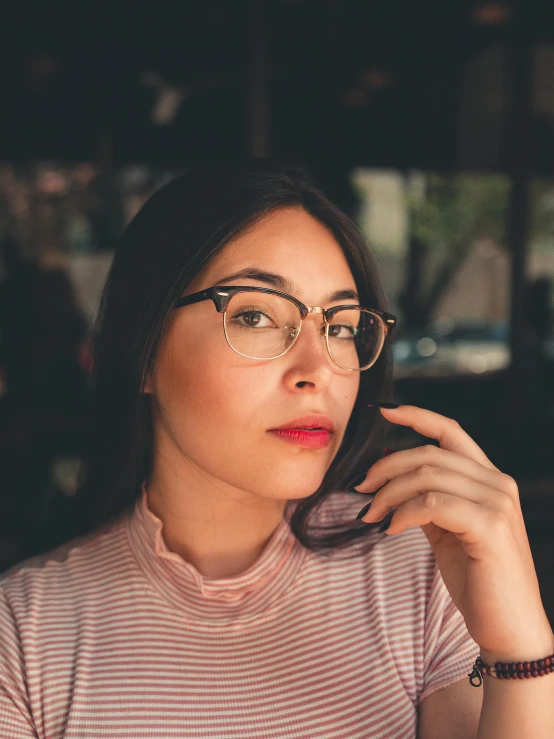 a woman with glasses sitting at a table, trending on pexels, nonbinary model, profile image, phone background, square glasses