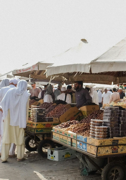 a group of people standing around a fruit stand, dau-al-set, brown and white color scheme, muslim, sprawling, panoramic