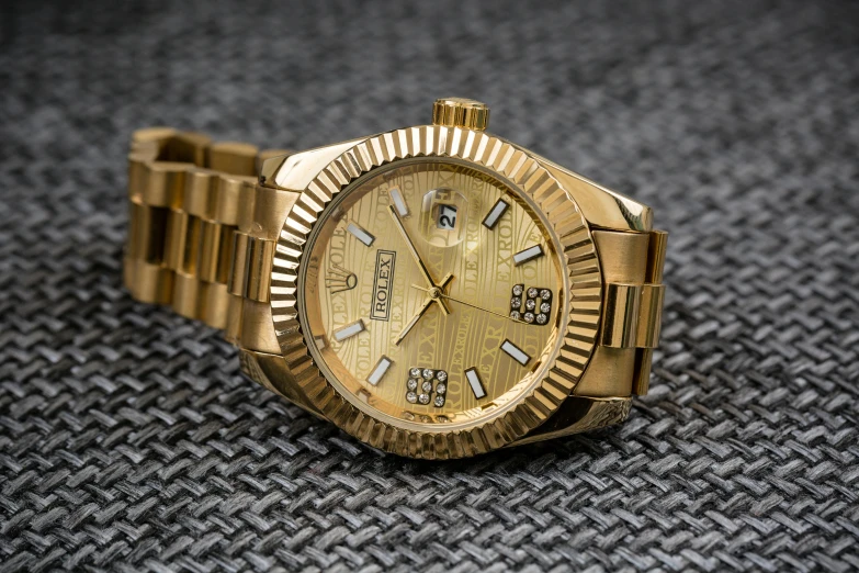 a close up of a watch on a table, a portrait, by Jason Felix, pexels contest winner, gold color scheme, rolex, youtube thumbnail, curvy build