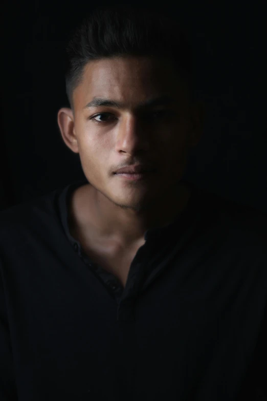 a man in a black shirt looking at the camera, inspired by Byron Galvez, pexels contest winner, sumatraism, portrait of depressed teen, side light, lgbtq, spotlight from face