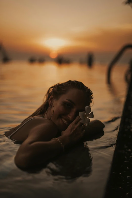 a woman laying on top of a body of water, during a sunset, profile image, cheeky smile, bali