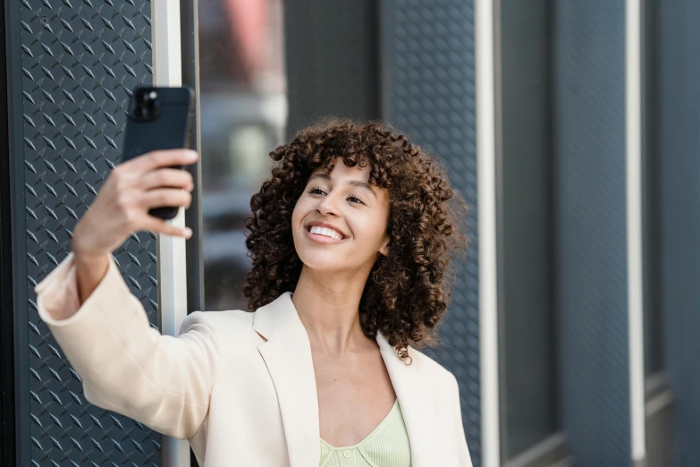 a woman taking a selfie with her cell phone, trending on pexels, brown curly hair, well lit professional photo, portrait of tall, uploaded