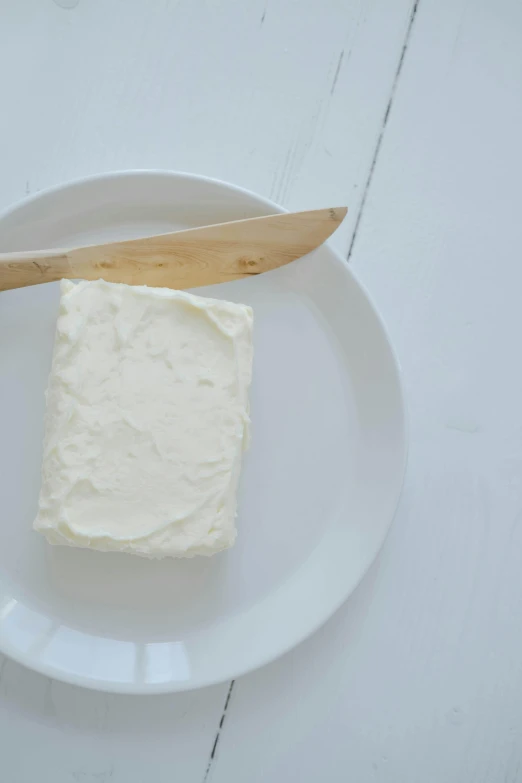 a piece of butter sitting on top of a white plate, by Jessie Algie, square, lightweight, wall, spatula