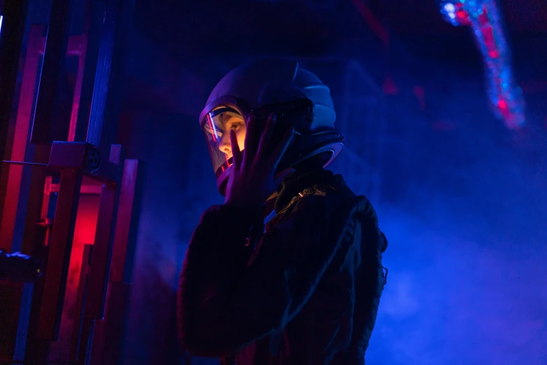 a man in a helmet talking on a cell phone, by Adam Marczyński, pexels contest winner, afrofuturism, atmospheric red lighting, 70's jetfighter pilot, in a pitch black room, pilot girl