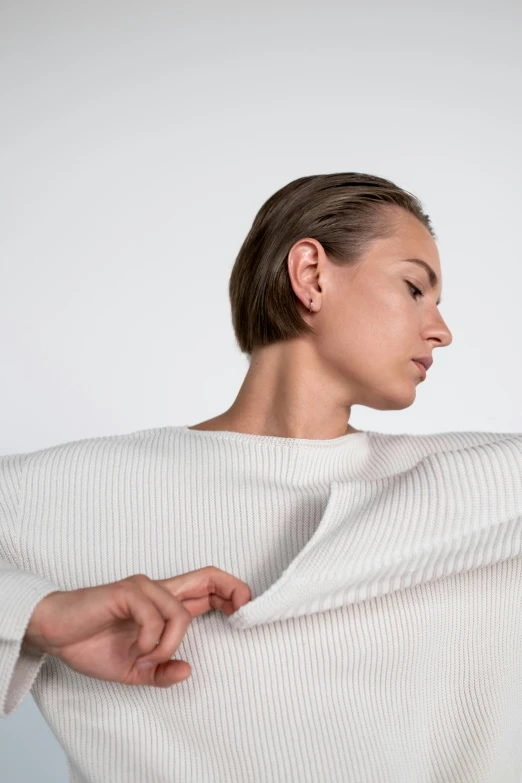 a woman in a white sweater posing for a picture, an album cover, inspired by Viktor de Jeney, trending on unsplash, issey miyake, lateral view, dezeen, on clear background