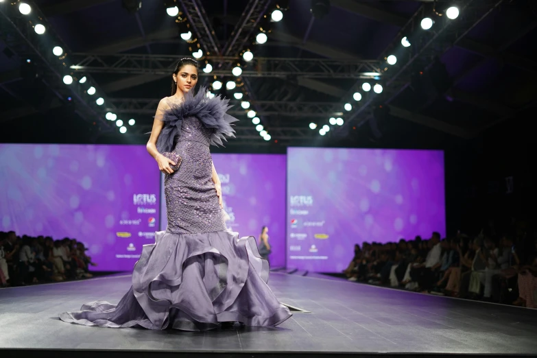 a woman in a purple dress walking down a runway, by reyna rochin, maya ali, wētā fx, frill, thumbnail