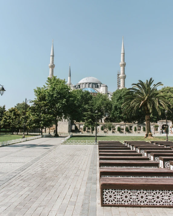 a row of benches sitting in front of a building, by Julia Pishtar, unsplash contest winner, hurufiyya, minarets, square, blue, lush surroundings