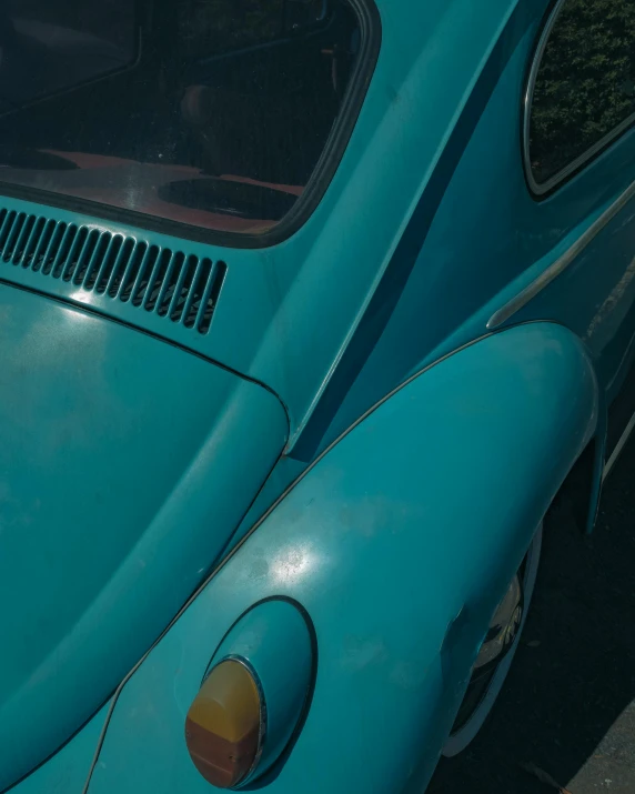 a blue car parked on the side of the road, an album cover, inspired by Elsa Bleda, unsplash contest winner, photorealism, beetle, ((greenish blue tones)), bottom body close up, trending on vsco