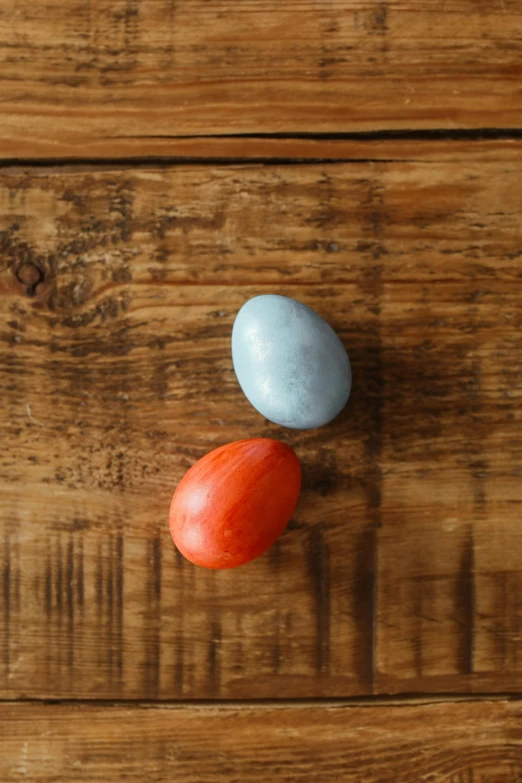 two eggs sitting on top of a wooden table, vermillion and cyan, carved soap, payne's grey and venetian red, mini model