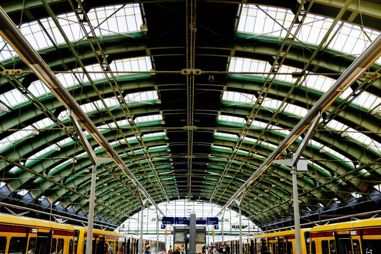 a train that is sitting inside of a train station, by Jacob van Utrecht, pexels, yellow and green, skylight open ceiling, square, panoramic