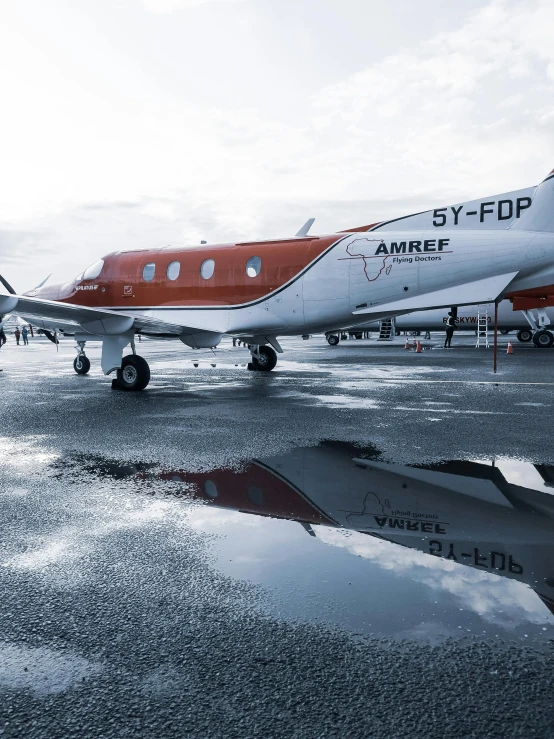 a small airplane sitting on top of an airport tarmac, a photo, by Andries Stock, private press, wet reflections, profile image, symmetrical 4k, shot with sony alpha 1 camera
