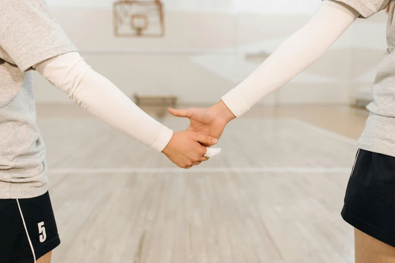 a couple of people holding hands in a room, basketball court, no - text no - logo, holding each other, instagram post