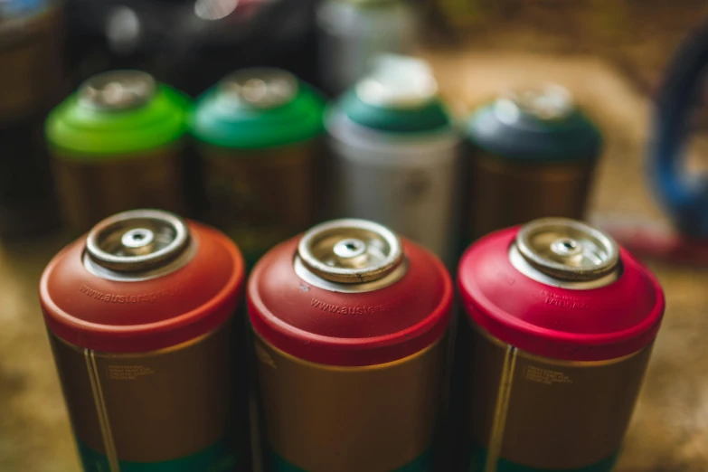 a group of batteries sitting on top of a table, an airbrush painting, by Thomas Häfner, unsplash, graffiti, vibrant red and green colours, cans, close up portrait shot, viridian and venetian red