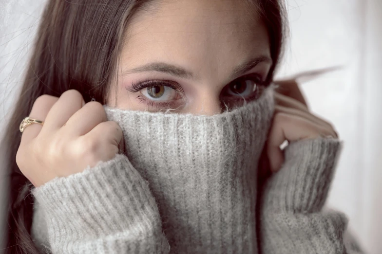 a woman wearing a sweater covering her face, trending on pexels, big brown eyes, grey, modelling, cold