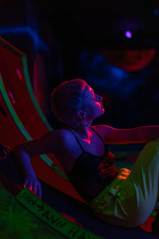 a woman sitting in a chair in the dark, interactive art, in a colorful tent, climbing, uv, teenager hangout spot