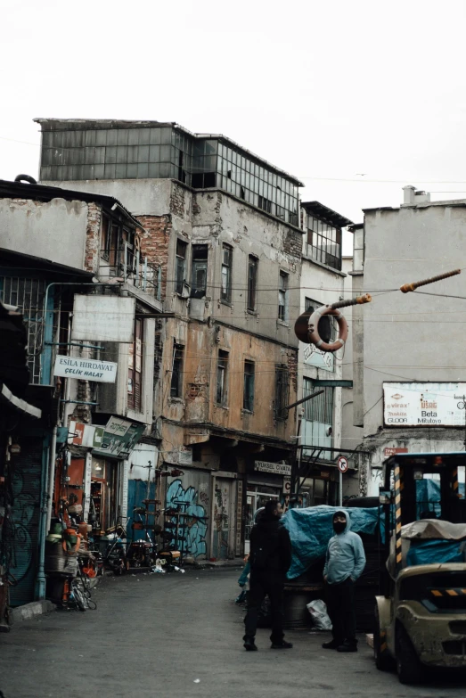 a group of people walking down a street next to tall buildings, abandoned buildings, hasan piker, vintage vibe, 1990s photograph