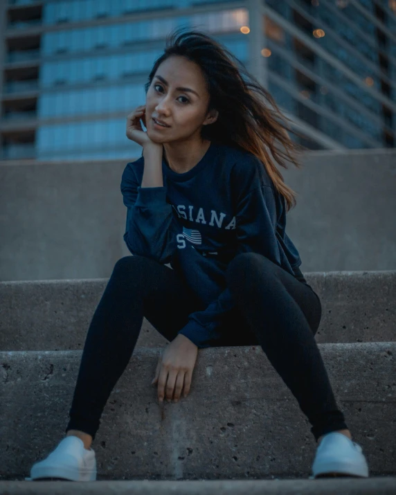 a woman sitting on some steps talking on a cell phone, an album cover, trending on unsplash, in a navy blue sweater, confident pose, slightly tanned, asian women