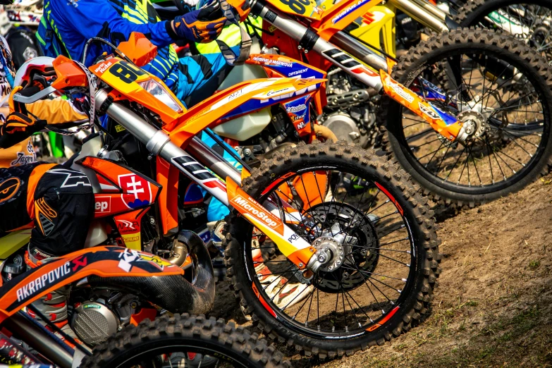 a group of dirt bikes parked next to each other, by Adam Marczyński, orange racing stripes, avatar image, colourful close up shot, thumbnail