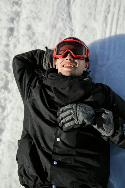 a man laying in the snow on a snowboard, inspired by Brian Snøddy, winking, laying down with wrists together, black, day time