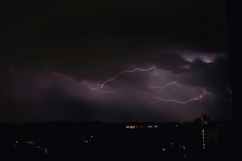 a lightning bolt in the sky over a city, by Niko Henrichon, pexels contest winner, happening, ☁🌪🌙👩🏾, dark stormy weather, hd footage, zoomed out shot