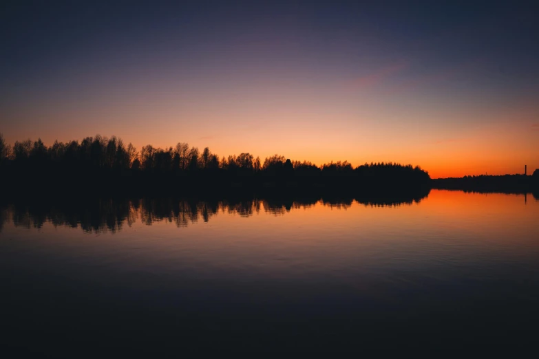 a body of water with trees in the background, by Jaakko Mattila, pexels contest winner, sunset colors, plain background, almost night, sunset warm spring