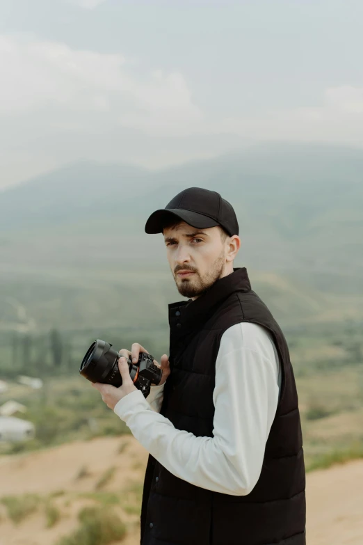 a man standing on top of a dirt road holding a camera, anton fadeev 8 k, headshot profile picture, overlooking a valley, orthodox