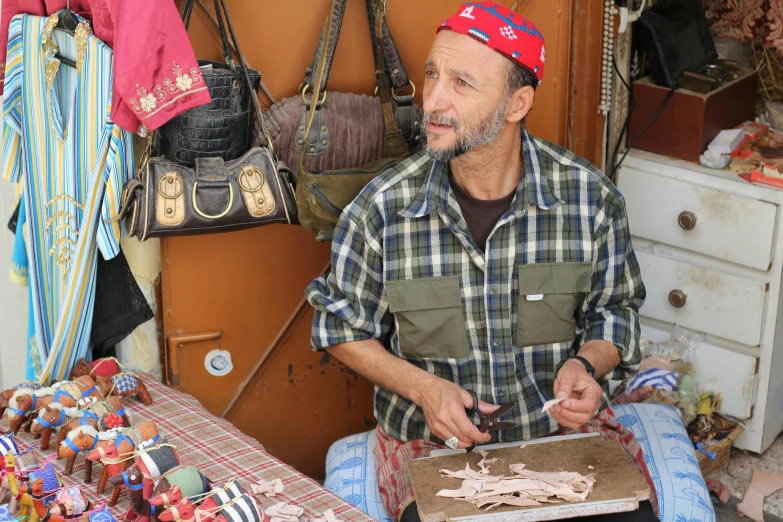 a man sitting at a table with a tray of food, crafts and souvenirs, covered in organic flesh meat, avatar image, street photo