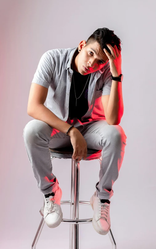 a man sitting on top of a metal stool, an album cover, inspired by Randy Vargas, pexels, casual pose, young male, profile image, looking serious