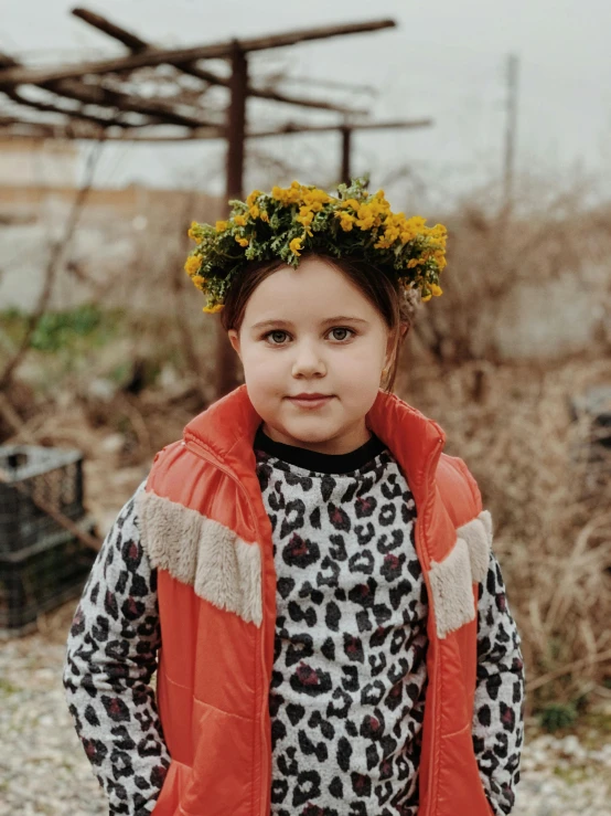 a little girl with a flower crown on her head, by Lucia Peka, pexels contest winner, wearing a turtleneck and jacket, ukraine. professional photo, orange jacket, wearing animal skin clothing