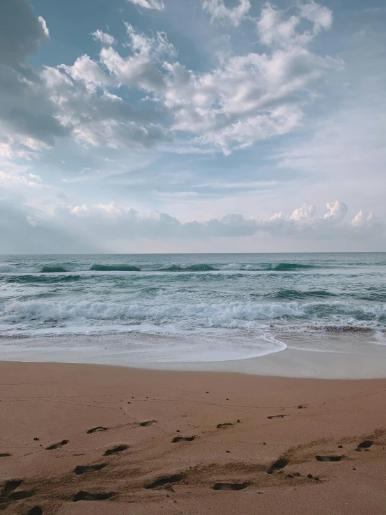 a man standing on top of a sandy beach next to the ocean, pexels contest winner, pristine rippling oceanic waves, manly, today\'s featured photograph 4k, footprints