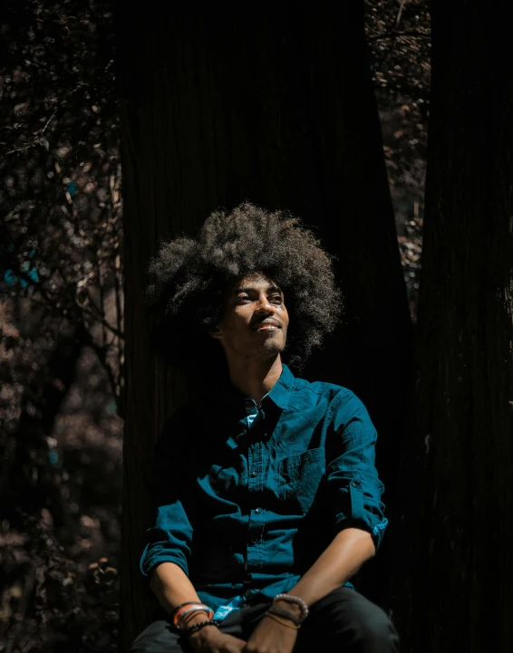 a man sitting on a log in the woods, by Cosmo Alexander, pexels contest winner, afro hair, ((portrait)), under the soft shadow of a tree, androgynous person