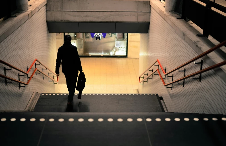 a man walking down a flight of stairs carrying a bag, by Daniel Seghers, pexels contest winner, modernism, underground scene, central station in sydney, late evening, thumbnail