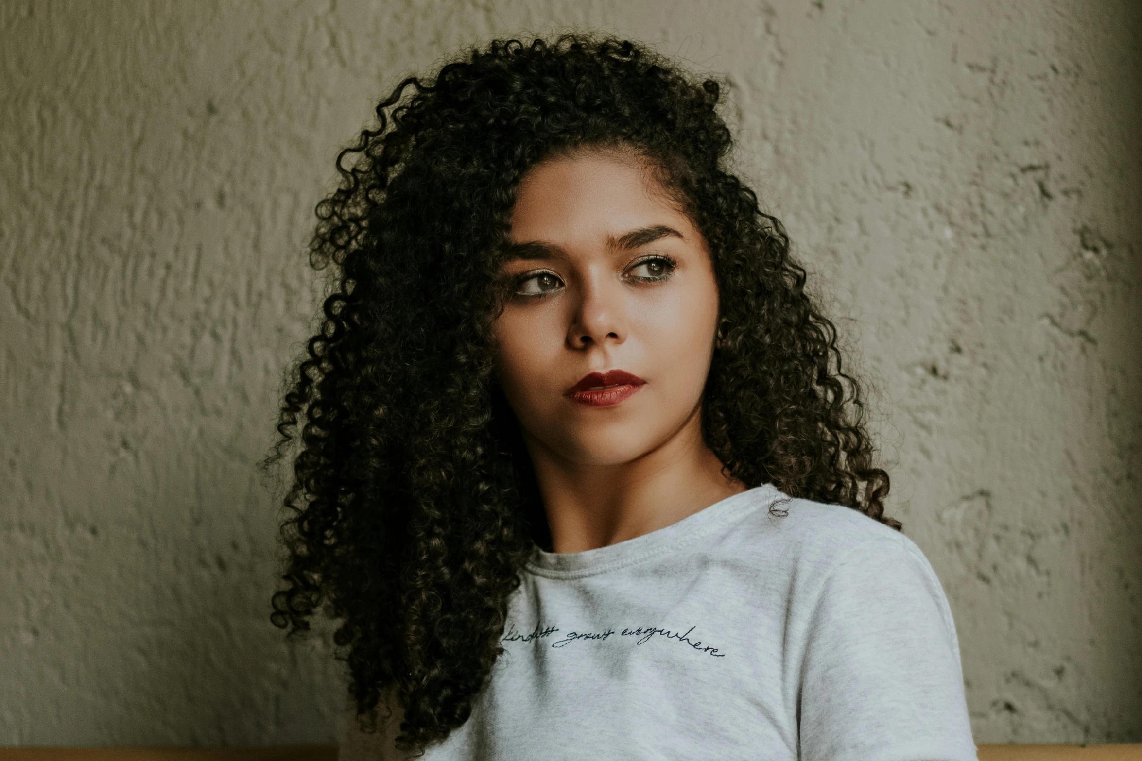 a woman with curly hair sitting on a couch, pexels contest winner, wearing a t-shirt, close up portrait photo, trending photo, headshot photo