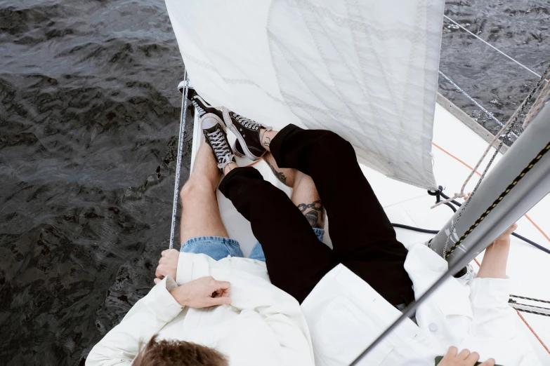 a man and a woman sitting on a sailboat, pexels contest winner, wearing white sneakers, white and black clothing, tumblr aesthetic, laying down