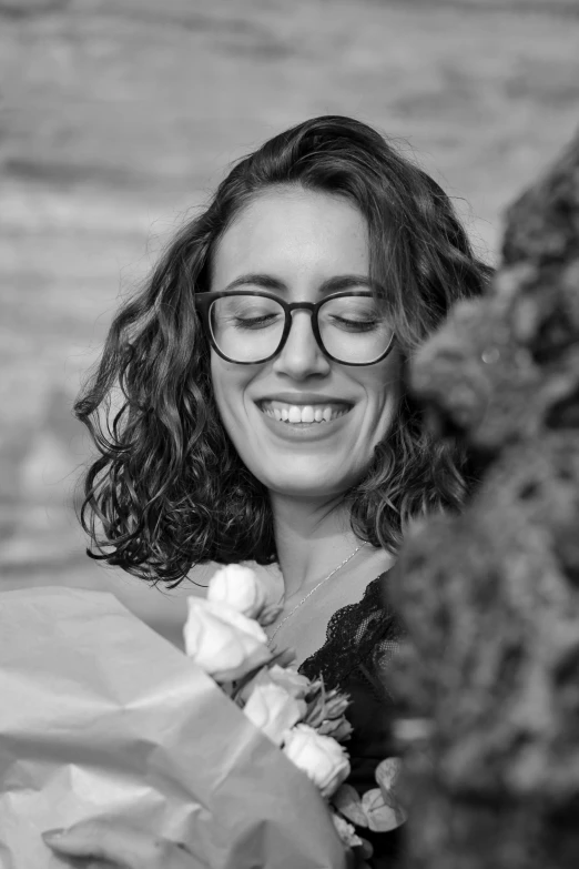 a black and white photo of a woman holding flowers, a black and white photo, antipodeans, wavy long black hair and glasses, dark short curly hair smiling, maia sandu hyperrealistic, giorgia meloni
