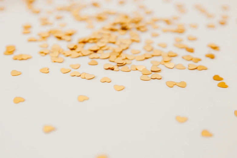 a white table topped with lots of gold confetti, by Emma Andijewska, trending on unsplash, several hearts, 3 mm, plain white background, background image