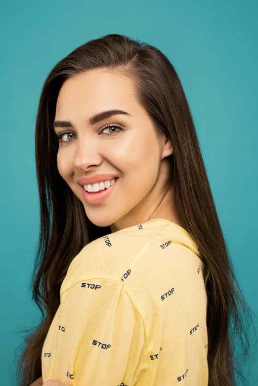 a woman in a yellow shirt smiles at the camera, trending on pexels, teal studio backdrop, madison beer, 15081959 21121991 01012000 4k, symmetrical nostrils