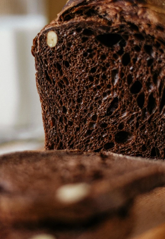 a loaf of bread sitting on top of a wooden cutting board, by Adam Marczyński, pexels contest winner, dark chocolate hair colour, trypophobia, side view close up of a gaunt, fully chocolate