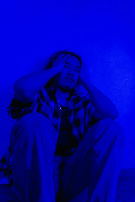 a man sitting on the ground with his head in his hands, an album cover, by Mark Arian, pexels, renaissance, dayglo blue, looking exhausted, post malone, brightly lit blue room