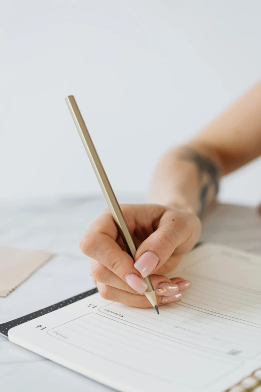 a woman sitting at a table with a pen in her hand, by Nicolette Macnamara, trending on unsplash, thin gold details, lined paper, set against a white background, holding pencil