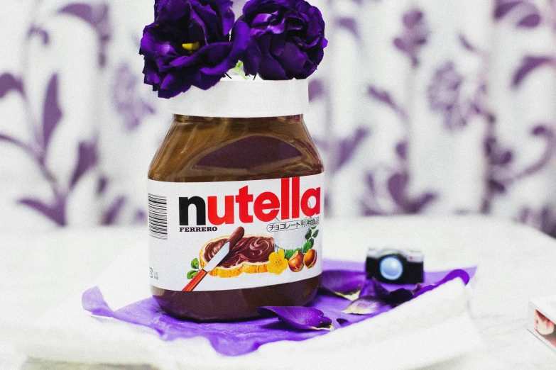 a jar of nutella sitting on top of a table, by Julia Pishtar, purple flowers, photoshoot, donatello, caramel