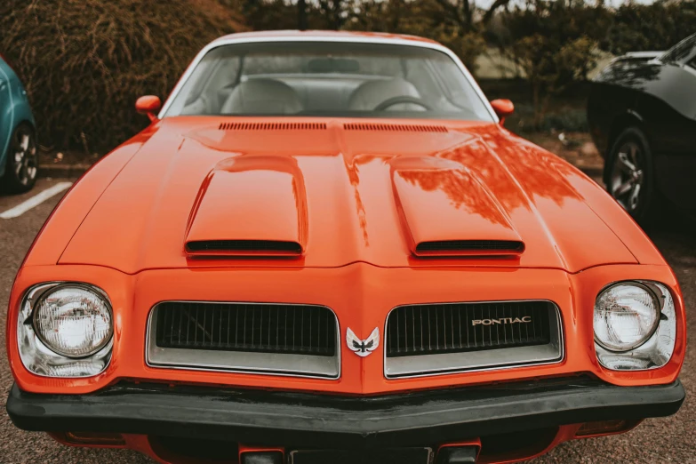 an orange pontiac car parked in a parking lot, pexels contest winner, 🦩🪐🐞👩🏻🦳, extremely detailed frontal angle, 1 9 7 4, modified