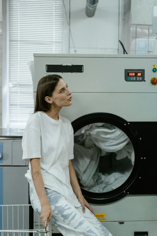 a woman standing in front of a washing machine, inspired by Elsa Bleda, pexels contest winner, with a lab coat, maxim shirkov, small manufacture, uniform off - white sky