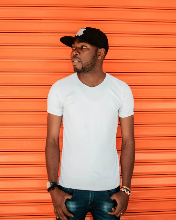 a man standing in front of an orange wall, pexels contest winner, black arts movement, dressed in a white t shirt, profile image, promotional image, a high angle shot